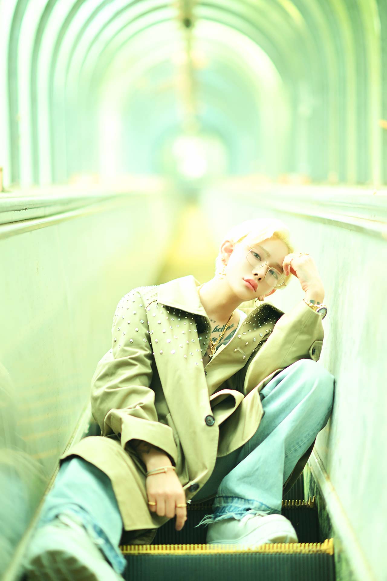 TOP DANDY TOKYO レオナルド レノピが静岡県の廃墟エスカレーターに座って額に手を添え、淡い光の中でアンニュイな表情を見せるホスホス ゼングラのカット