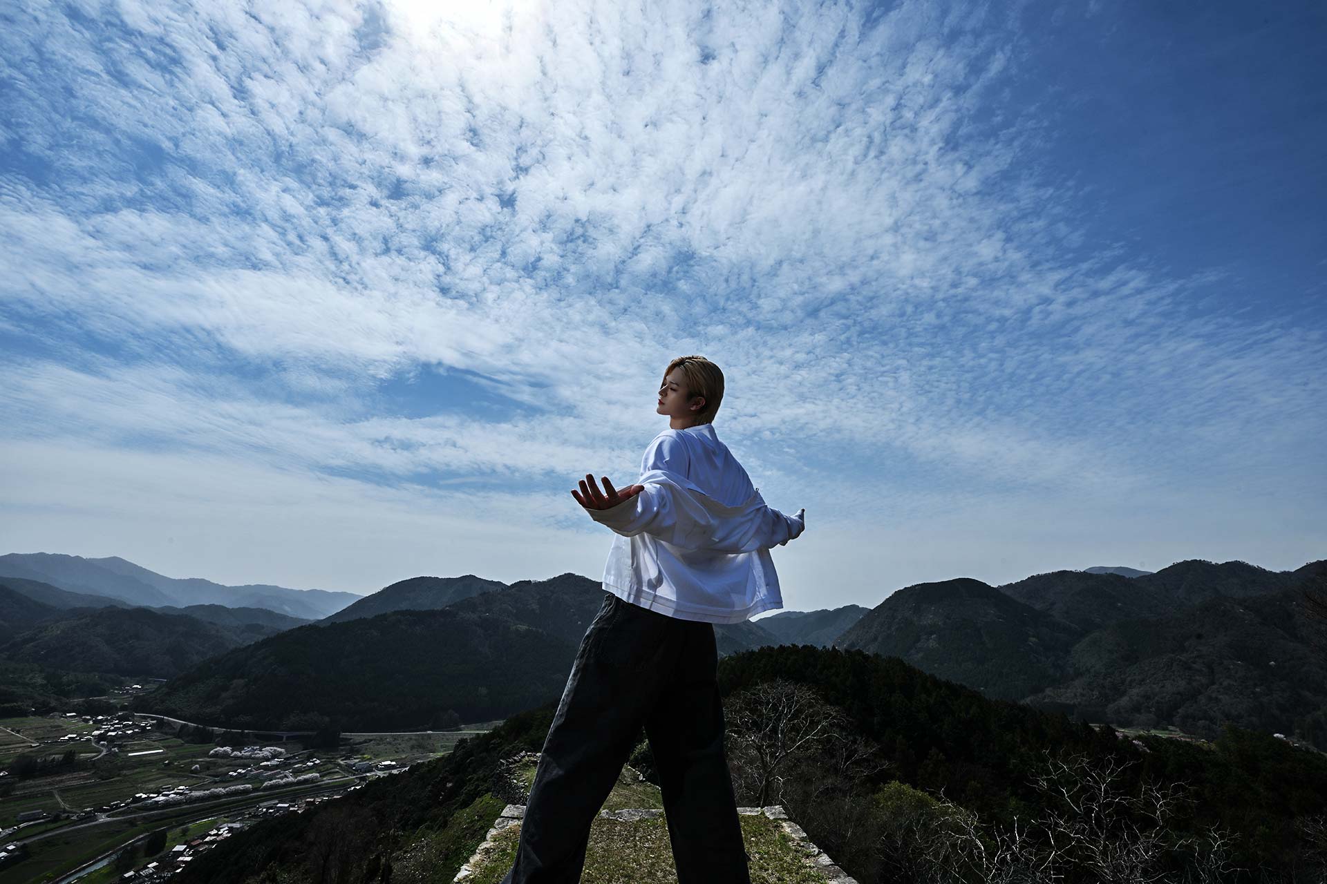 Leo 美月が山の絶景を背景に両手を広げる全身写真