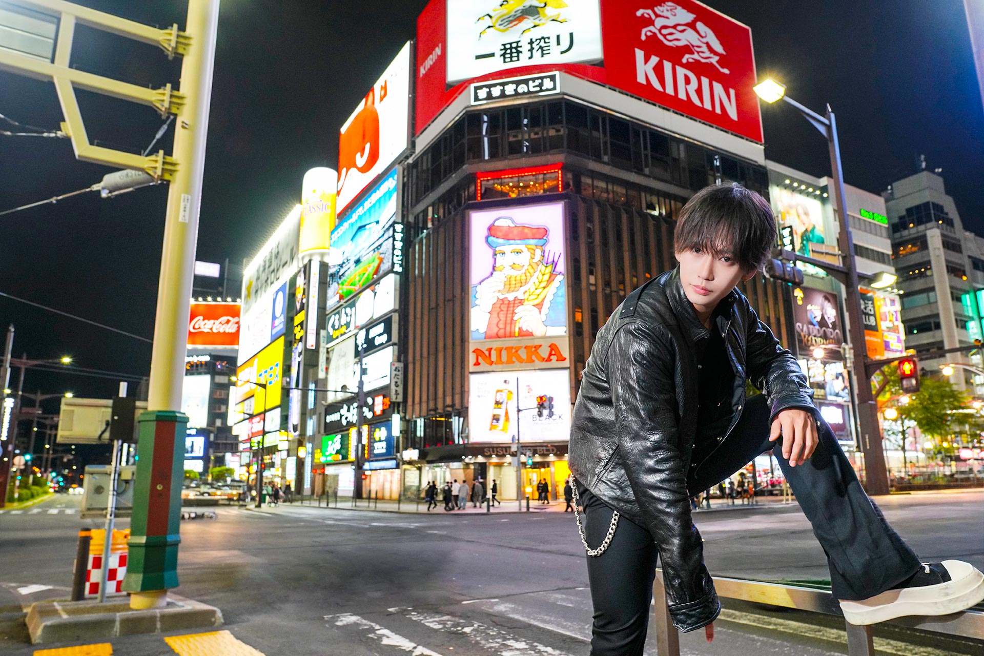 HAREM -総本店- 早瀬 優がすすきの交差点のランドマークを背に低い姿勢で視線を向ける一枚