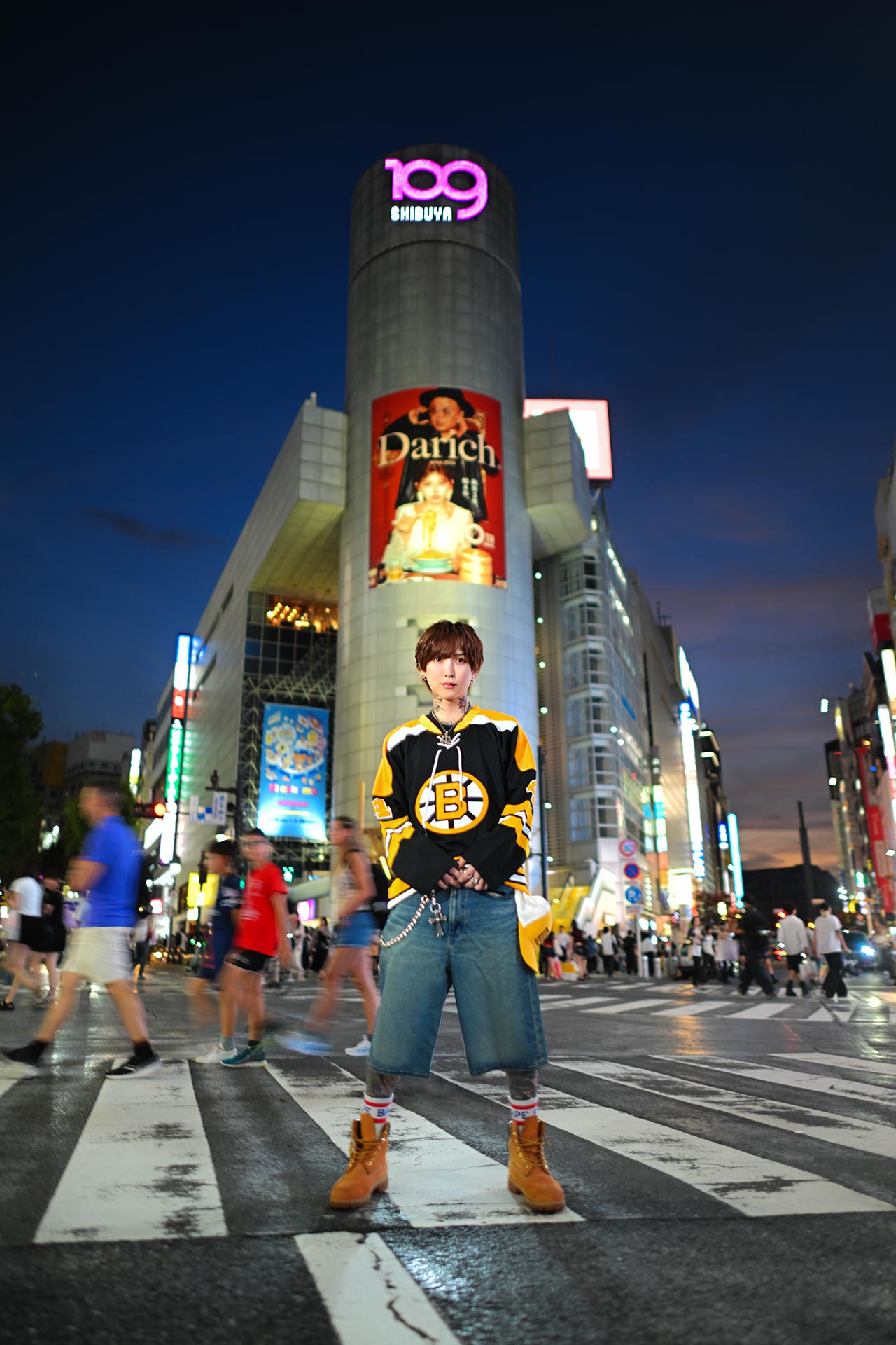 夜の渋谷スクランブル交差点で行き交う人々の中に立つ天音恋愛